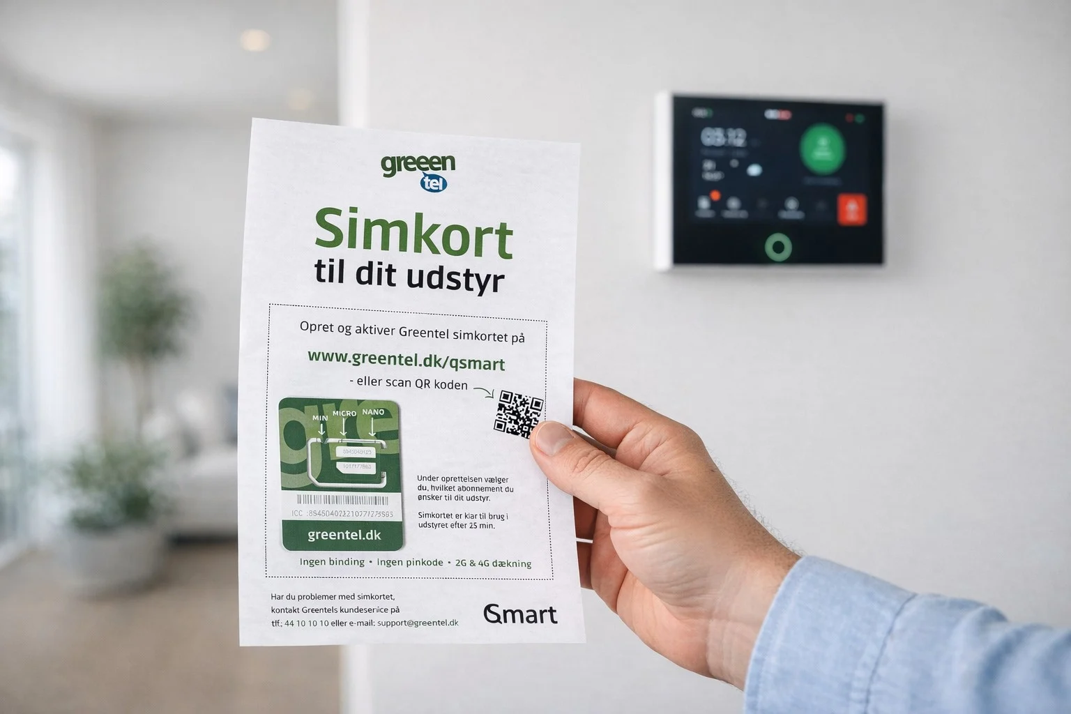 Hånd holder Greentel SIM-kort start pakke med DanGear HEIMDALL PRO touchskærm alarmpanel hængende i baggruden