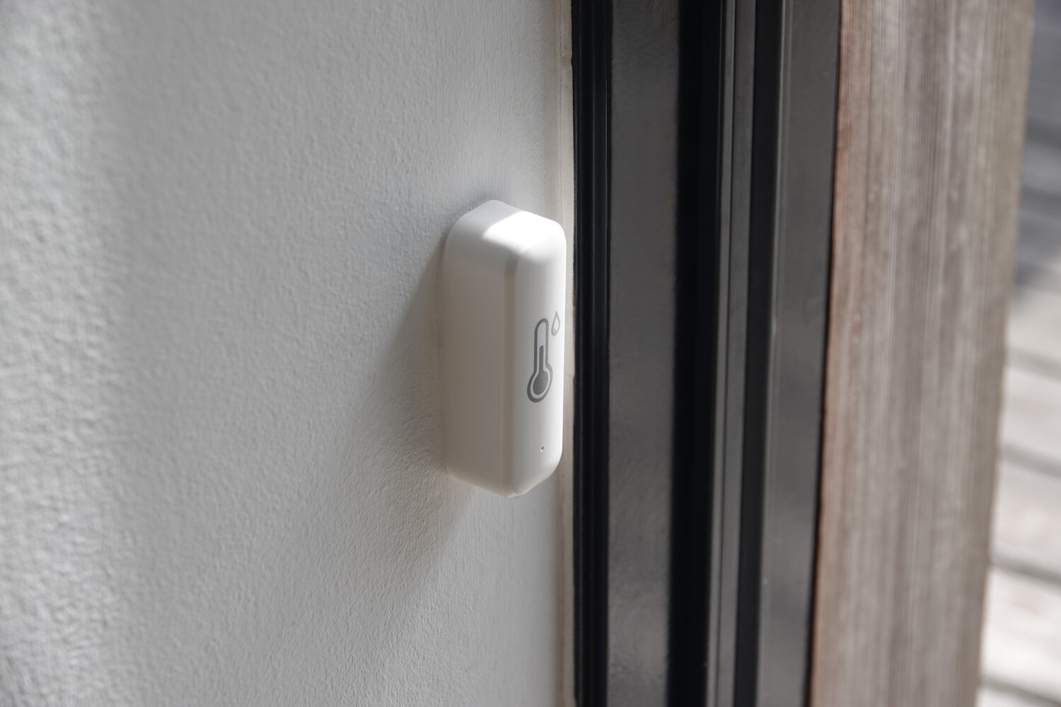 WiFi termometer og fugtighedsmåler tæt på fra siden, monteret på væg